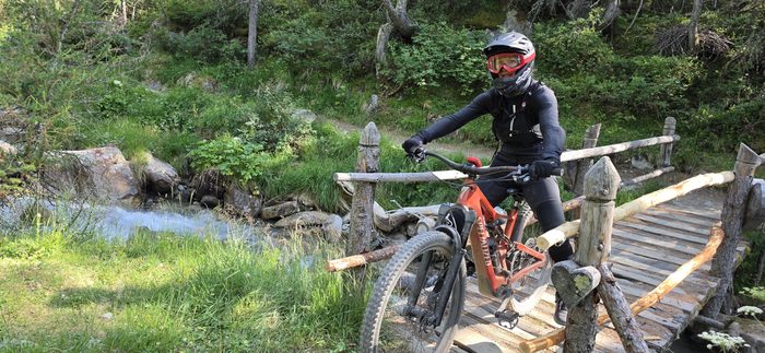 Rowerzysta na drewnianym mostku nad górskim potokiem